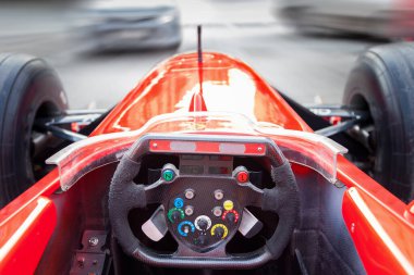 Şehir yarışı sırasında kırmızı bir Formula 1 spor araba kullanan bir sürücü...