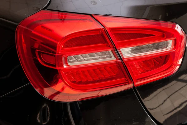 Close-up di lampu rem LED belakang berwarna merah pada mobil hitam — Stok Foto