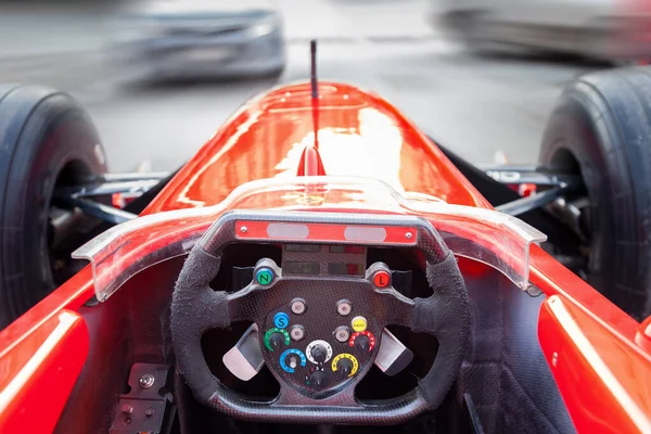 En förare som kör en röd Formel 1 sportbil under en stad ras en — Stockfoto