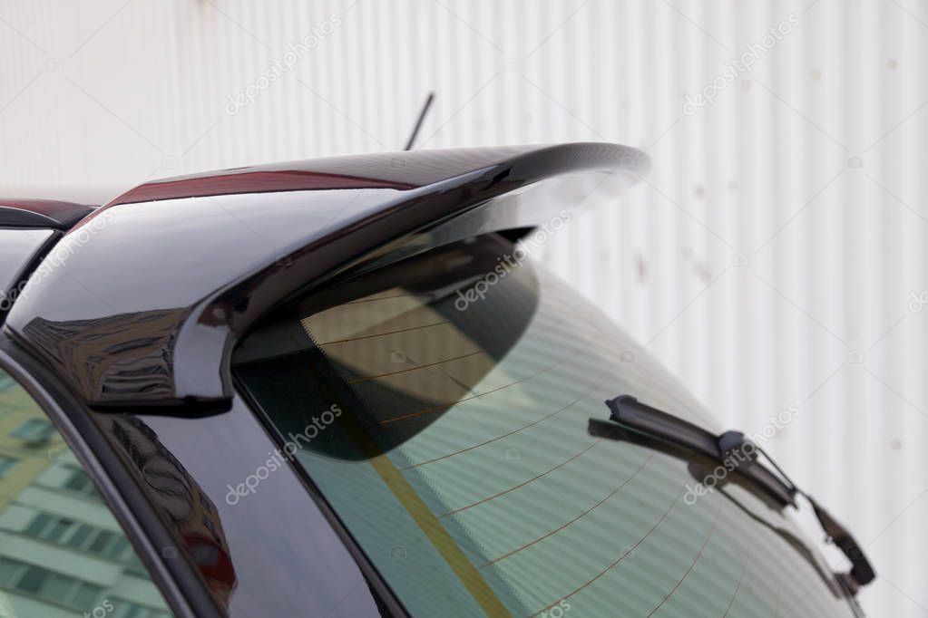 View of the trunk lid of a black car with a plastic spoiler over