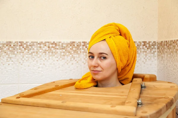 Uma jovem menina bonita de aparência caucasiana em um barril de cedro — Fotografia de Stock