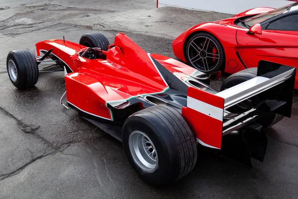 Two red racing sports cars on the street near the garage box. — Stock Photo, Image