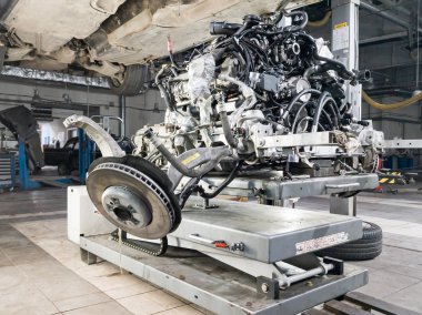 Tamir için kaldırılan ikinci el bir araba ve altında da kopuk bir araba.