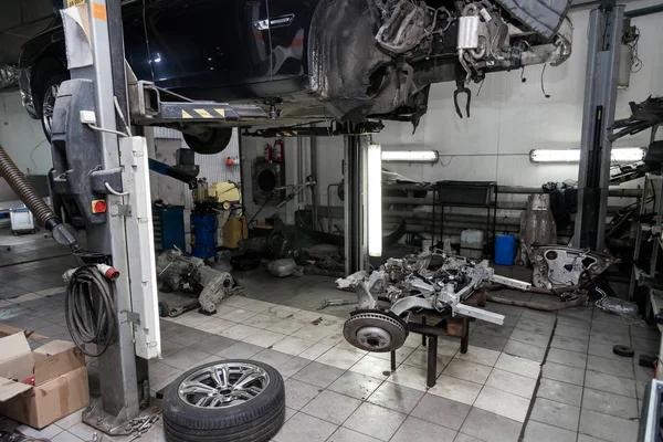 Um carro usado velho sem roda, levantado em um elevador para reparo e u — Fotografia de Stock