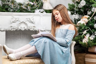 Küçük tatlı güzel kız Noel ağacının yanında bir bank ve...