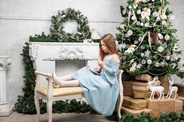 Petite jolie fille mignonne un banc près du sapin de Noël et f — Photo