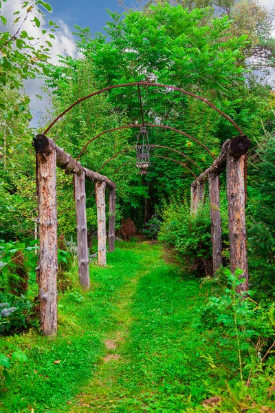 Un túnel arqueado de madera rodeado de árboles verdes y plantas con — Foto de Stock