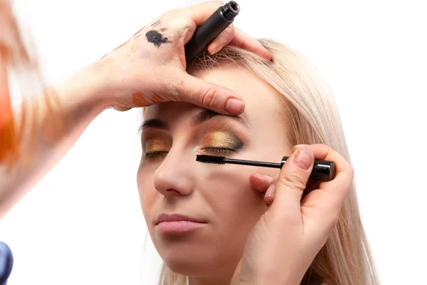 Makeup artist puts on an oriental-style make-up with gold and gr