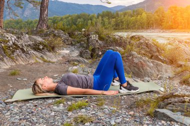 Sarışın güzel kız taş grou üzerinde yatan bir ısınma yapıyor