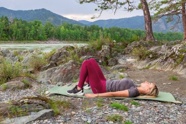Sarışın güzel kız taş grou üzerinde yatan bir ısınma yapıyor