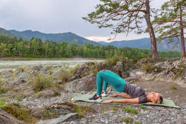 Sarışın güzel kız taş grou üzerinde yatan bir ısınma yapıyor