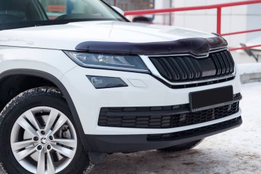 Beyaz yeni Skoda Kodiaq. Kar arabasının önüne park ediyor.