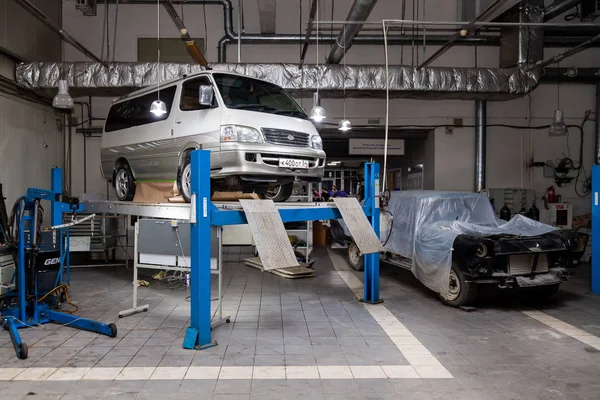 Blanco coche usado Toyota Hiace van levantado en un ascensor para la reparación — Foto de Stock