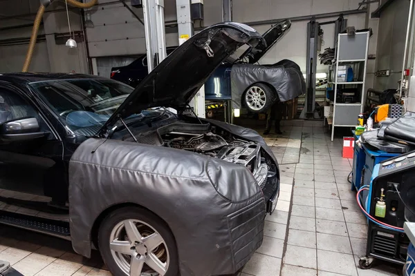 Carro preto desmontado com capuz openo na oficina levantada em — Fotografia de Stock