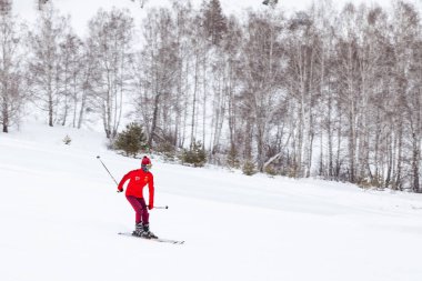 Bir kayakçı, dağdan kayarak beyaz karların üzerinden kayıyor.