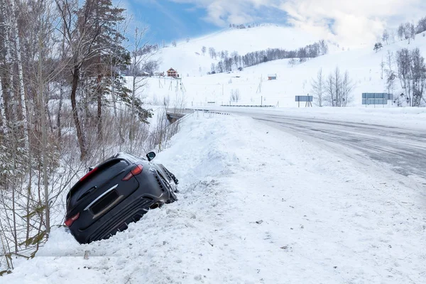 Accident on a winter snowy track with a black car skidding and f