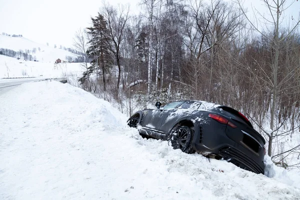 Accident on a winter snowy track with a black car skidding and f