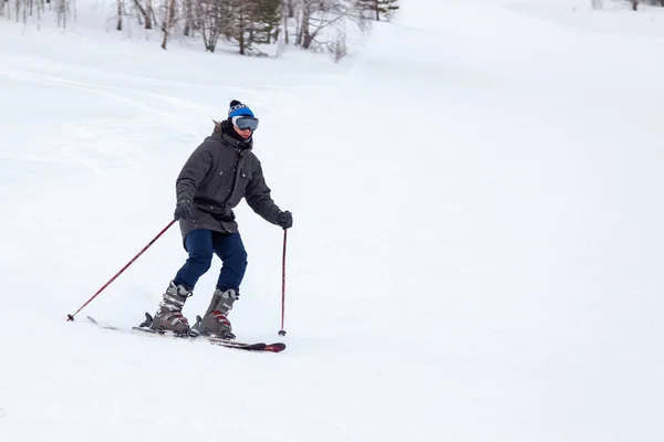 Лыжник спускается с горы по белому снегу в спорте — стоковое фото
