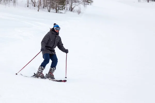 A man skier slides down the mountain over white snow in a sports — Stock Photo, Image