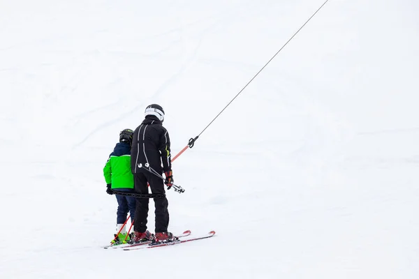 A man father and his son skier climbs a mountain through the whi — Stock Photo, Image