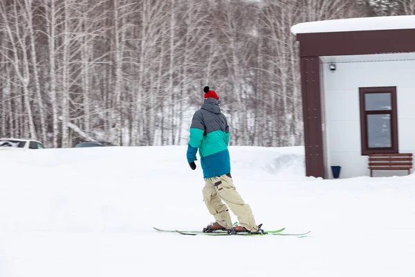 Egy férfi síelő csúszik le a hegyről a fehér hó felett egy sportban. — Stock Fotó