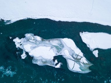 Kar ve ezilmiş buzla mavi ve yeşil bir nehrin havadan görünüşü 