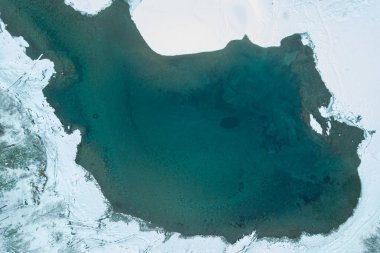 Kışın karlı, mavi ve yeşil bir göl manzarası 