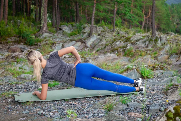 Sarışın güzel kız taş grou üzerinde yatan bir ısınma yapıyor
