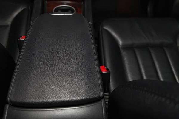 Close-up on the car front armrest with black leather trim, butto — 스톡 사진