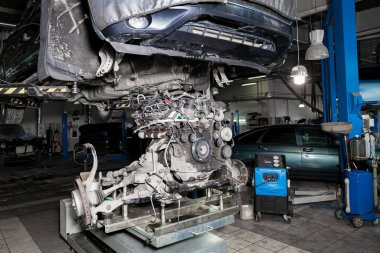 Replacement used engine on a table mounted under raised car on l