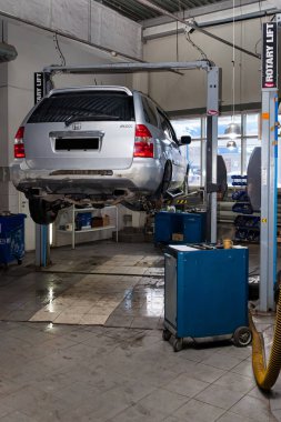 One silver used car Acura MDX raised on a lift for repairing the