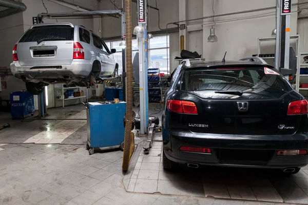 Two used cars Acura MDX and Luxgen raised on a lift for repairin