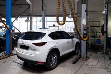 One white used car Mazda CX-5 on a lift for repairing the chassi clipart