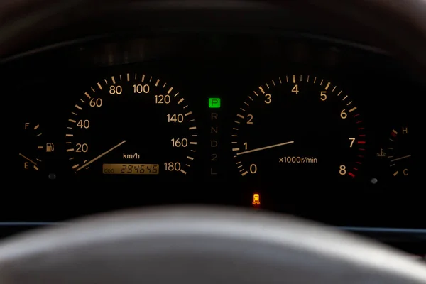 The dashboard of the car is glowing white at night with a speedo