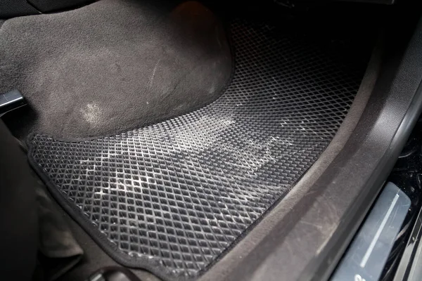 Dirty car floor mats of black rubber under passenger seat in the