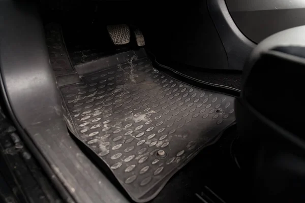 Dirty car floor mats of black rubber with gas pedals and brakes