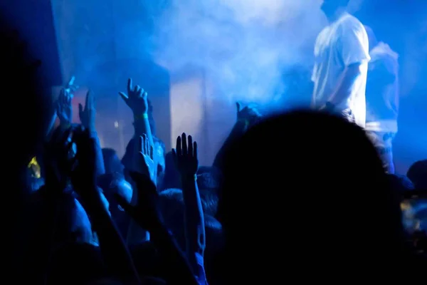 Publiczność z podniesionymi dłońmi na festiwalu muzycznym z kolorowymi ligh — Zdjęcie stockowe
