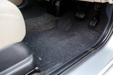 Gaz pedalları ve frenleri olan siyah halı paspasları. 