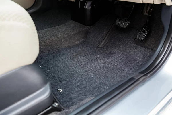 Чистые коврики для пола автомобиля из черного ковра с педалями газа и тормозами — стоковое фото