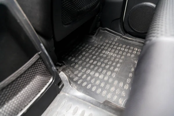 Clean car floor mats of black rubber under rear passenger seat in the workshop for the detailing vehicle before dry cleaning. Auto service industry. Interior of sedan.