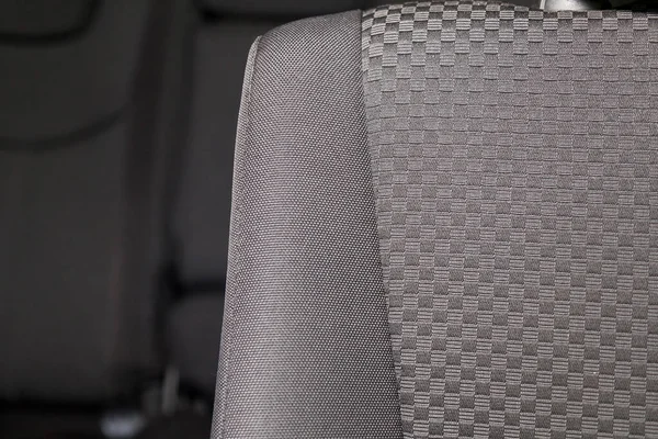 Upholstery of the seats of the passenger compartment of a luxury car with black fabric material in a workshop for hauling vehicles with a seam of thread.