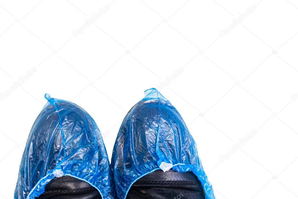 Top view of two legs in boots wrapped in blue shoe covers in a hospital while waiting for a doctor's appointment on white isolated background.  Coronavirus