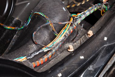 Kablo tamirhanesinde çok renkli turuncu ve yeşil kablolar, konnektörler ve terminaller bulunan geniş kablo ve elektrikçiler arabaya elektrik ve dijital sinyal bağlamak ve iletmek için