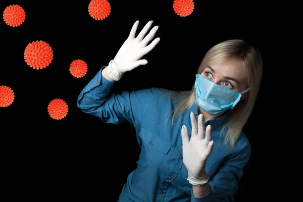 The woman is afraid of contracting coronavirus and is protected by rubber gloves and a medical mask from the attack of molecules of the bacteria covid-19.