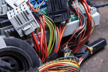 Ağ onarımı sırasında servis veya atölyede çalışan bir mühendis veya tamirci tarafından arabanın düğümlerinde bağlanan çok renkli elektrik kabloları.