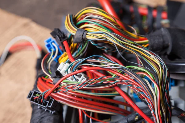 A bunch of multi-colored electrical wires interconnected in the nodes of a car during network repair by an engineer or mechanic in a service or workshop.