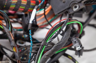Çok renkli kablolar arasında bulanık bir arkaplandaki siyah yalıtım bandıyla bir güç kanalının yakın plan görüntüsü. Bir geliştiricinin uzak çalışmasında dijital internet ağı.