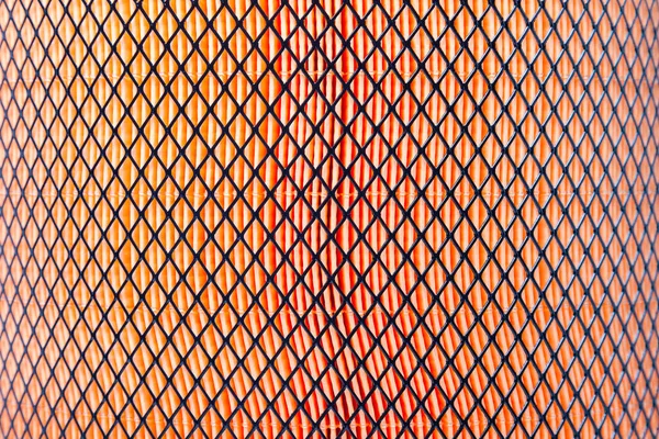 Orange pattern of porous material covered by black mesh. Truck air filter closeup. Designer drawing pattern on the desktop wallpaper.