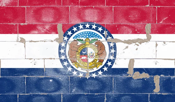 National flag of the US state of Missouri against a background of red blue and white stripes is a round emblem with two brown bears and stars painted on brick concrete wall street on Independence Day