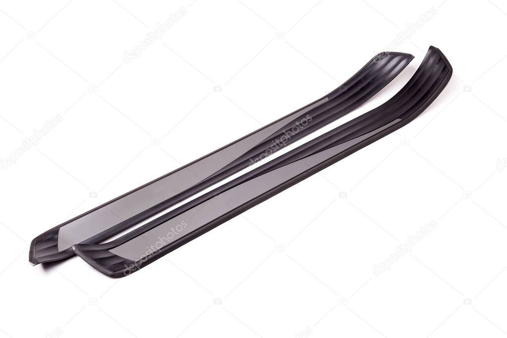 A pair of black plastic decorative door sills in an automobile parsing for sale or repair in a workshop on a white isolated background in a photo studio.